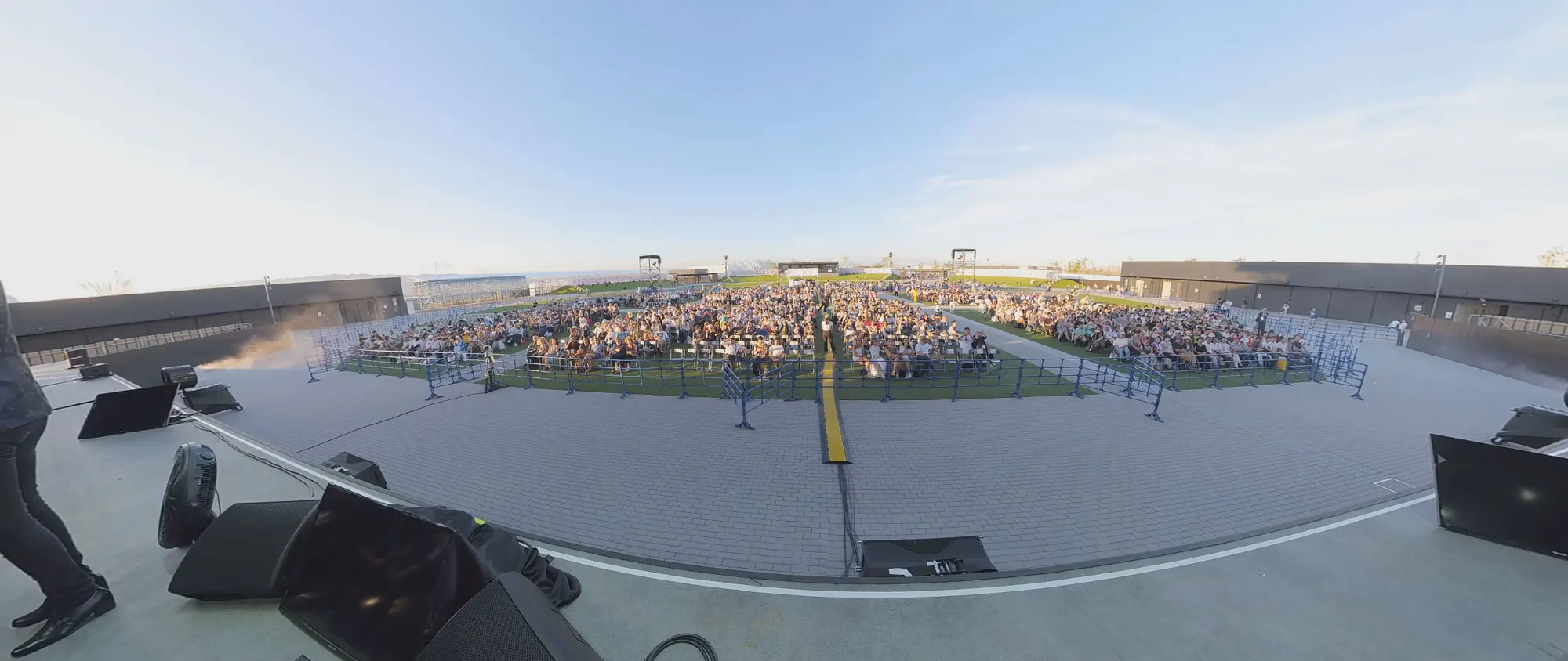 L’Arena Matsuri vista dal palco: il pubblico seduto sul prato, il cielo della sera, ai lati gli altoparlanti.